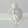 Ceramiczne aniołki siedzące szkliwione na biało. Długość 12cm, szerokość 7 cm, wysokość 12. Aniołek