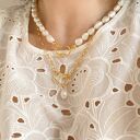 Złoty naszyjnik z ozdobnym zapięciem i naturalną perłą