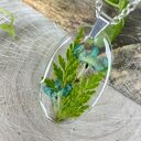 Owalny wisiorek z liśćmi i kwiatami w żywicy - handmade z suszonych roślin
