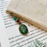 Zakładka do książki wykonana z elementów metalowych w kolorze zielonej miedzi ozdobiona opalizującym kocim oczkiem 6 mm, przekładką wysadzaną