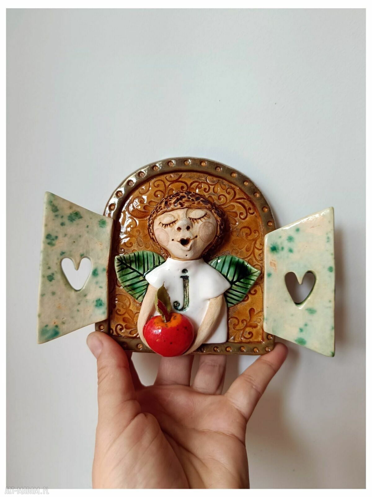 Ceramiczny anioł z jabłuszkiem w okiennicy