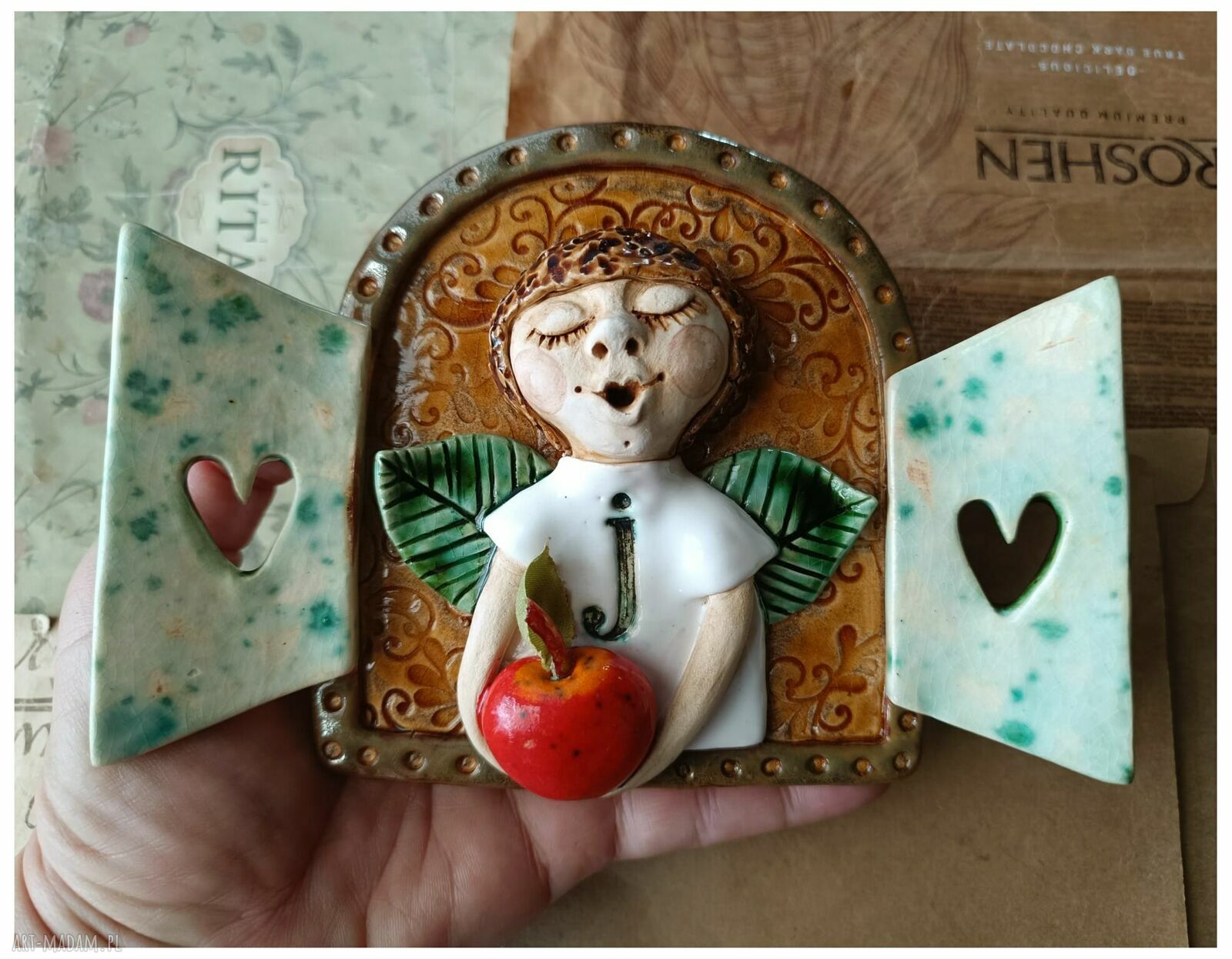 Ceramiczny anioł z jabłuszkiem w okiennicy