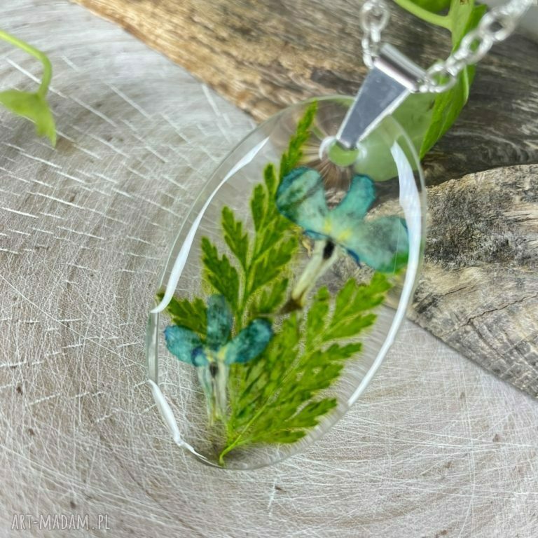 Owalny wisiorek z liśćmi i kwiatami w żywicy - handmade z suszonych roślin