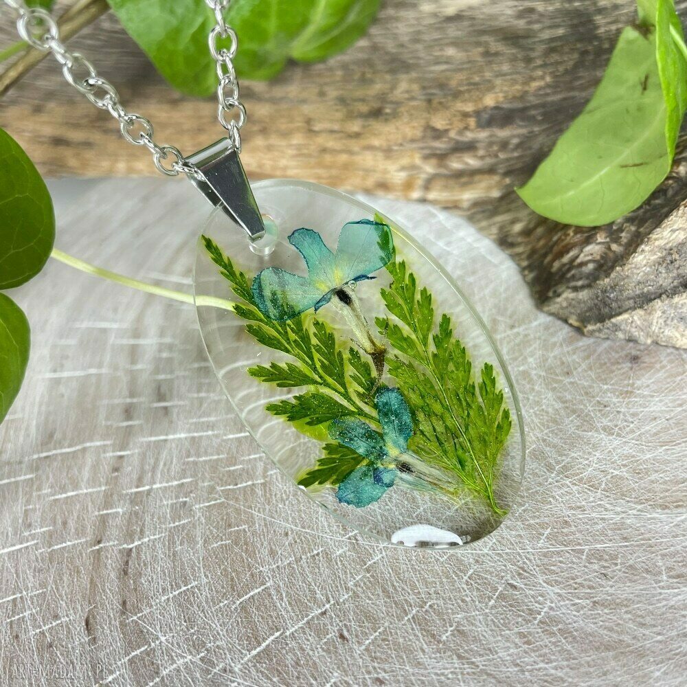 Owalny wisiorek z liśćmi i kwiatami w żywicy - handmade z suszonych roślin